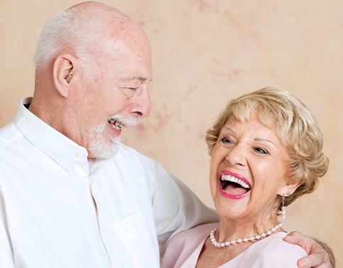 Older couple smiling after denture tooth replacement