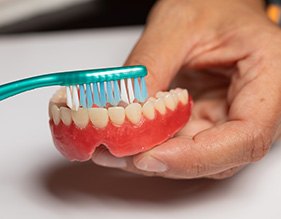 Man brushing his dentures