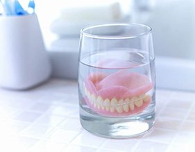 Dentures soaking in a glass