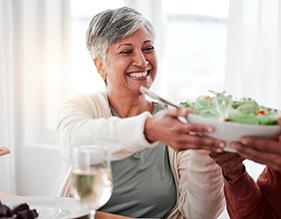 Smiling woman grabbing bowl of salad