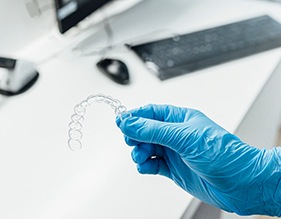 Dentist with blue glove holding clear aligner