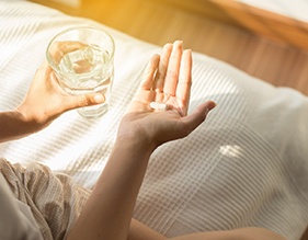 Woman holding a pill and water