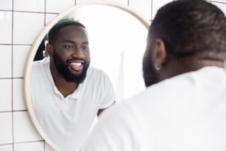 Man smiling while looking at reflection in mirror