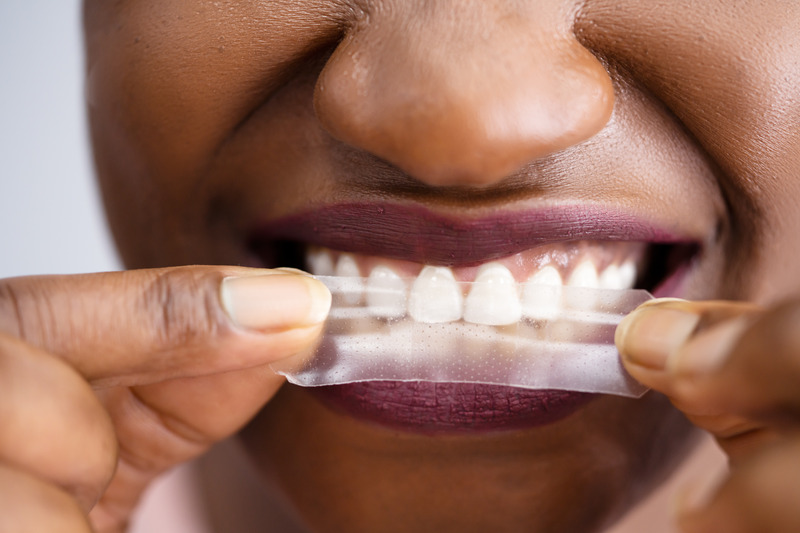 Patient using a teeth whitening strip