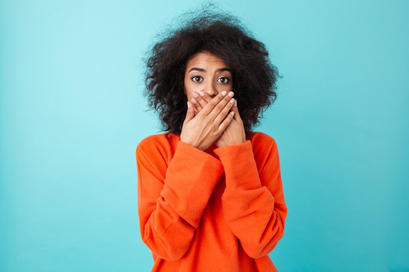 A woman using both hands to cover her mouth